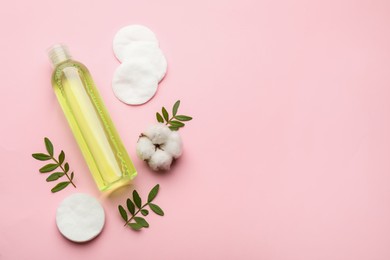 Photo of Cotton pads, flower, leaves and makeup removal product on pink background, flat lay. Space for text