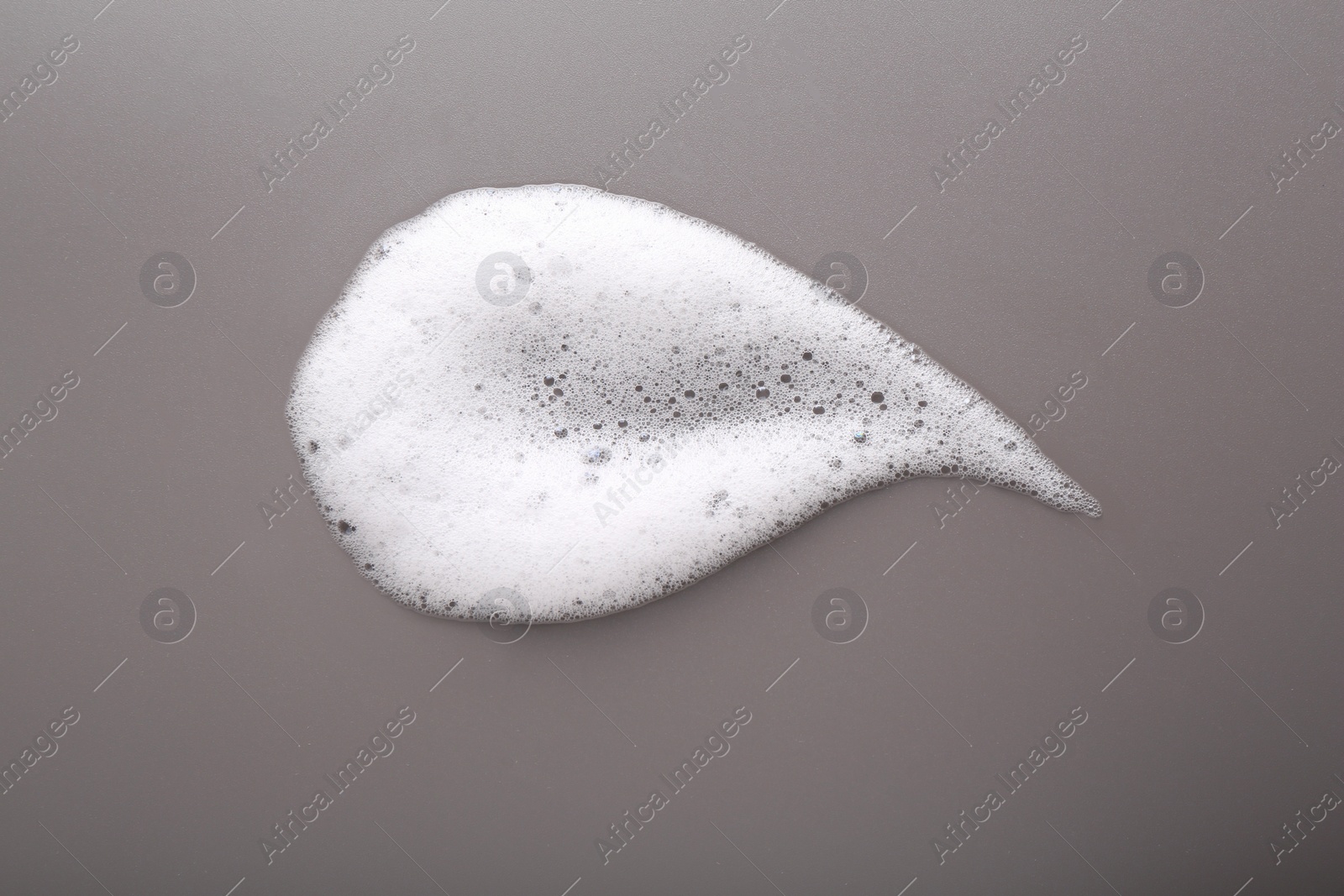 Photo of White foam with bubbles on grey background, top view