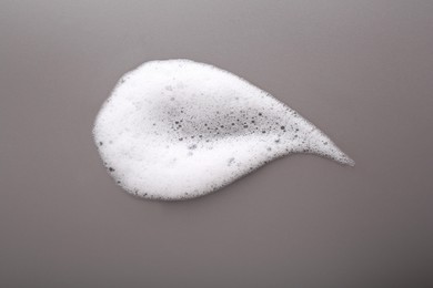 Photo of White foam with bubbles on grey background, top view