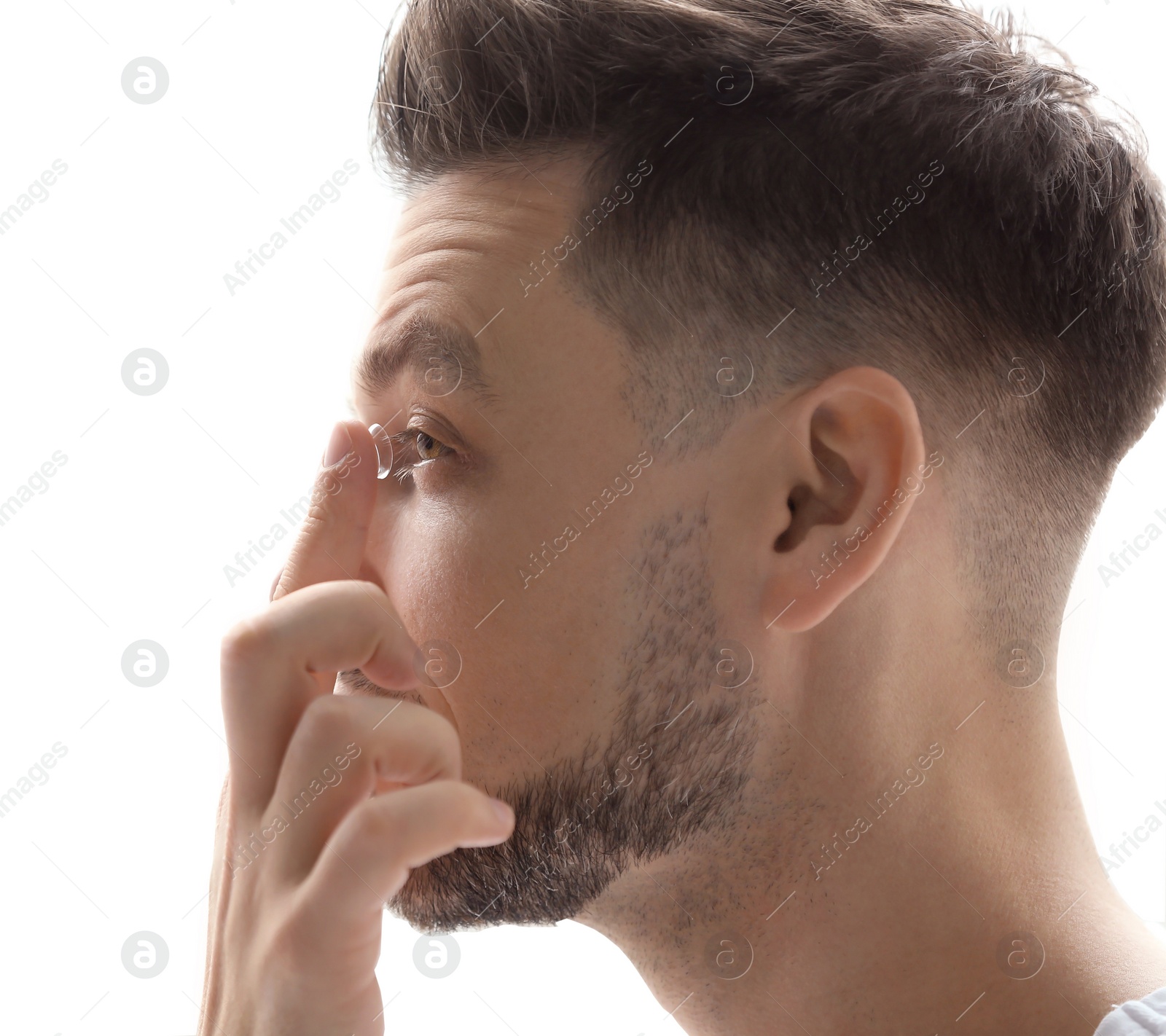 Photo of Young putting contact lens in his eye on white background