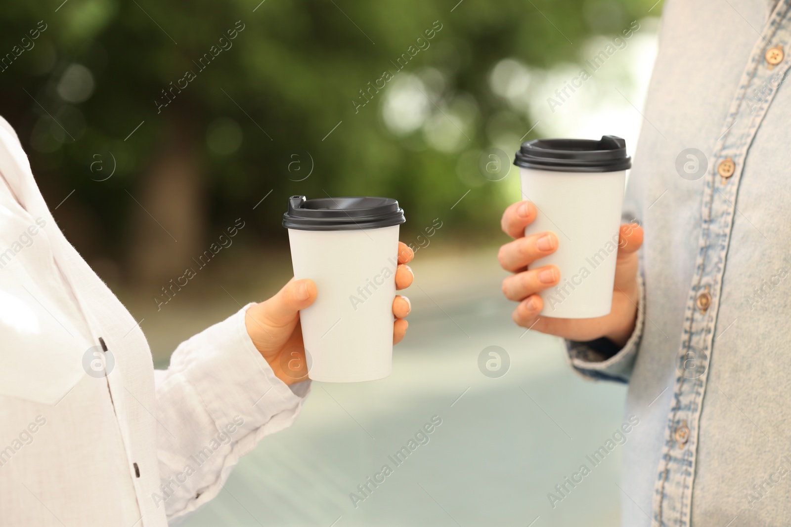 Photo of Women holding takeaway paper cups outdoors, closeup. Coffee to go