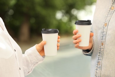 Women holding takeaway paper cups outdoors, closeup. Coffee to go