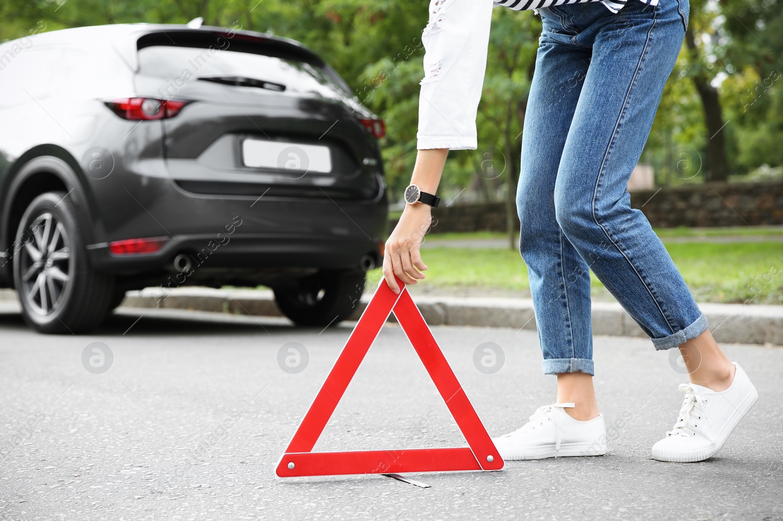 Photo of Woman putting emergency stop sign near broken car, closeup