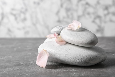 Photo of Spa stones and flower petals on grey table. Space for text