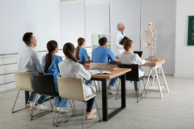 Photo of Medical students and professor studying human skeleton anatomy in classroom