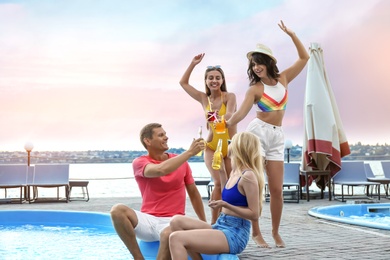 Photo of Group of happy people with refreshing drinks enjoying fun pool party