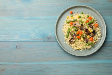 Photo of Delicious bulgur with vegetables and mushrooms on light blue wooden table, top view. Space for text