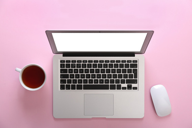 Photo of Modern laptop and cup of tea on pink background, flat lay