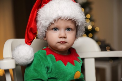 Photo of Baby in cute elf costume sitting on chair at home. Christmas outfit