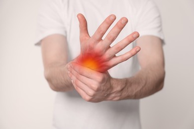 Image of Arthritis symptoms. Man suffering from pain in his hand on light background, closeup