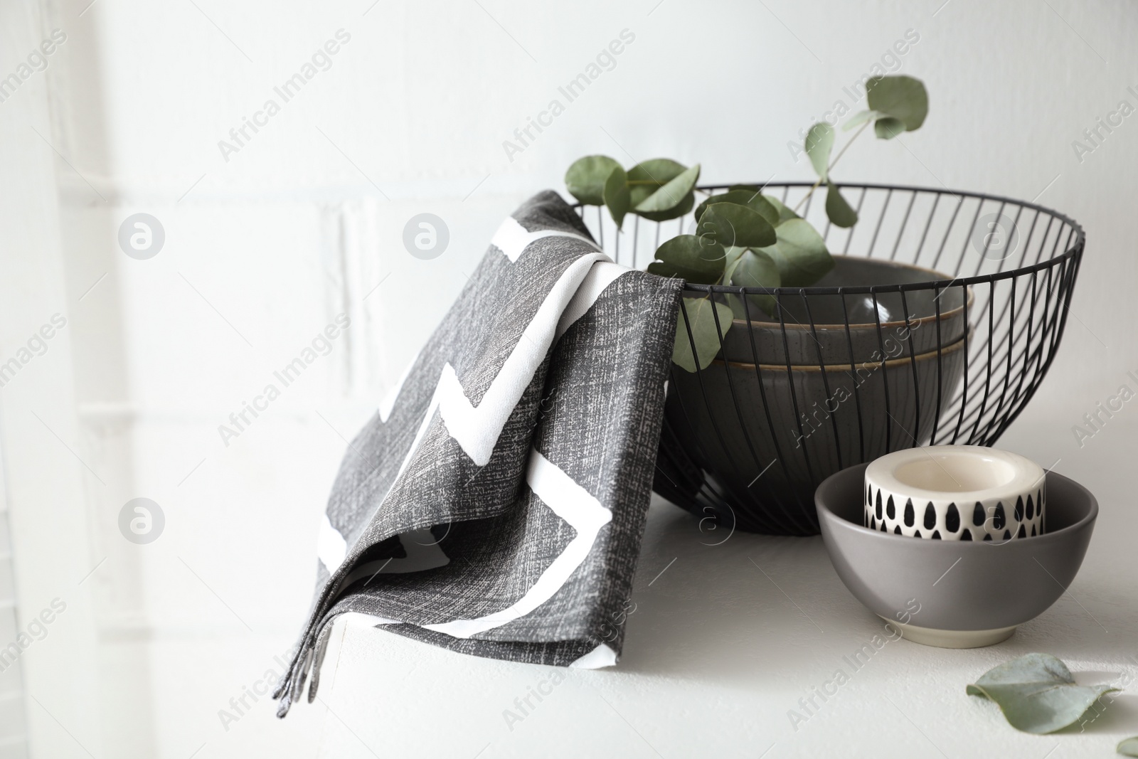 Photo of Stylish dishware and green eucalyptus branches on white table indoors, space for text