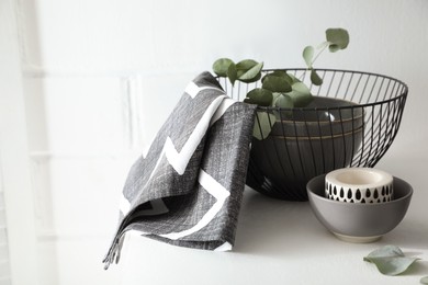 Stylish dishware and green eucalyptus branches on white table indoors, space for text