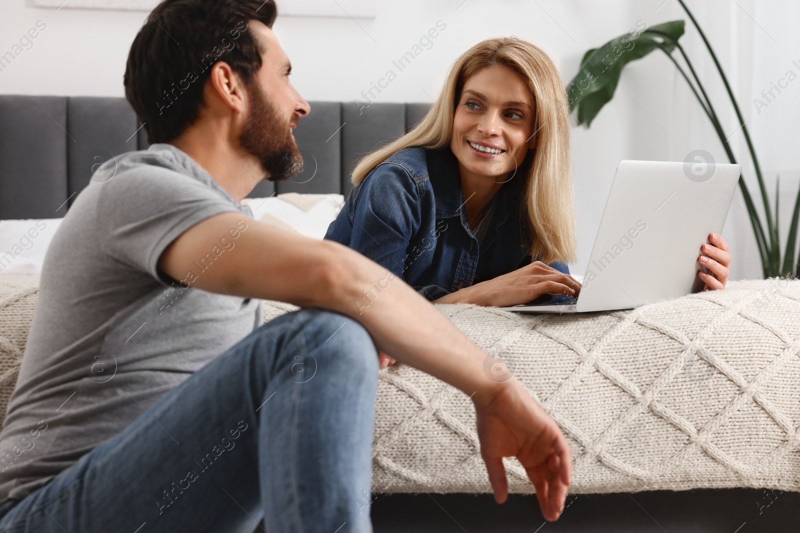 Photo of Happy couple spending time together and using laptop at home