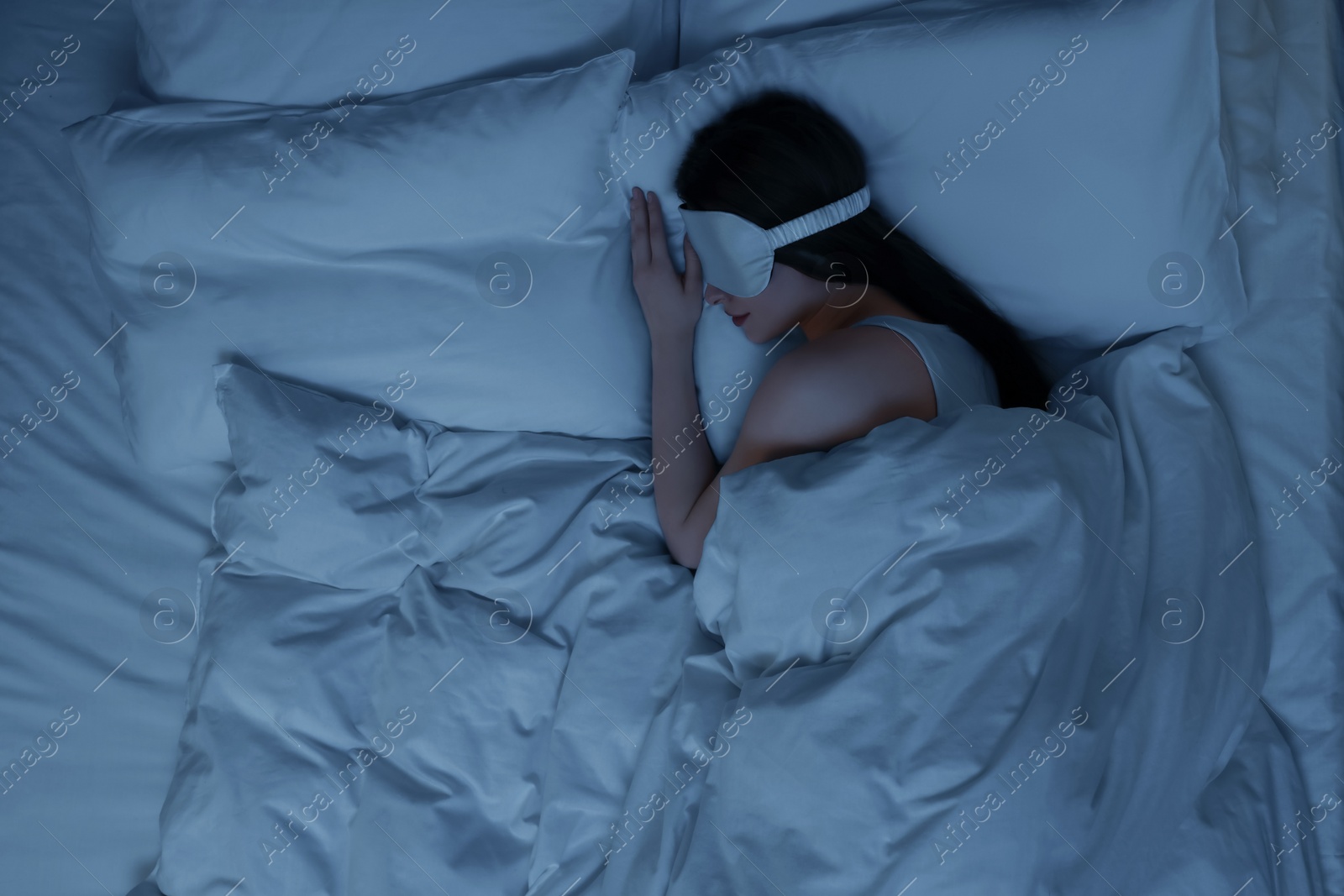 Photo of Woman with mask sleeping in bed at night, top view