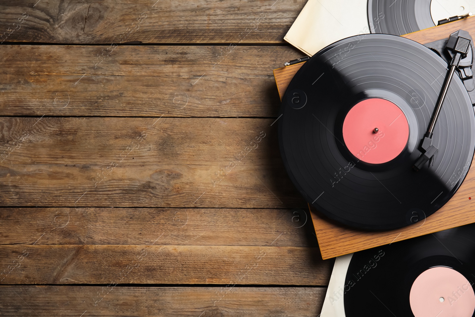 Photo of Modern player and vinyl records on wooden background, flat lay. Space for text
