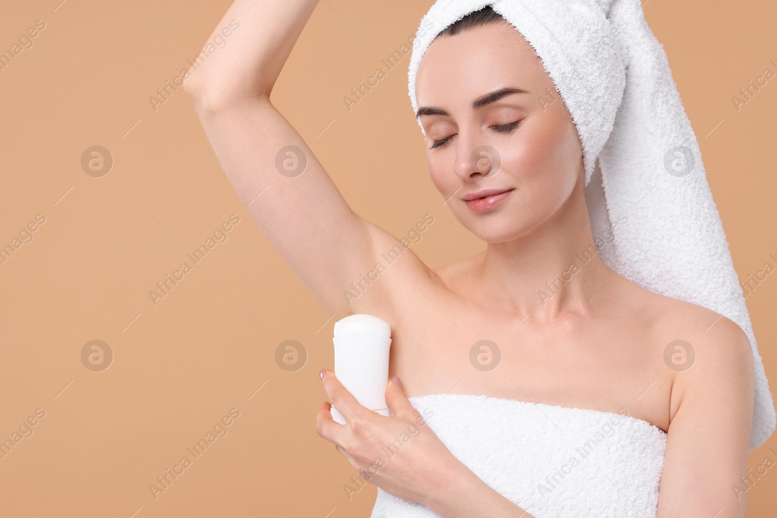 Photo of Beautiful woman applying deodorant on beige background, space for text