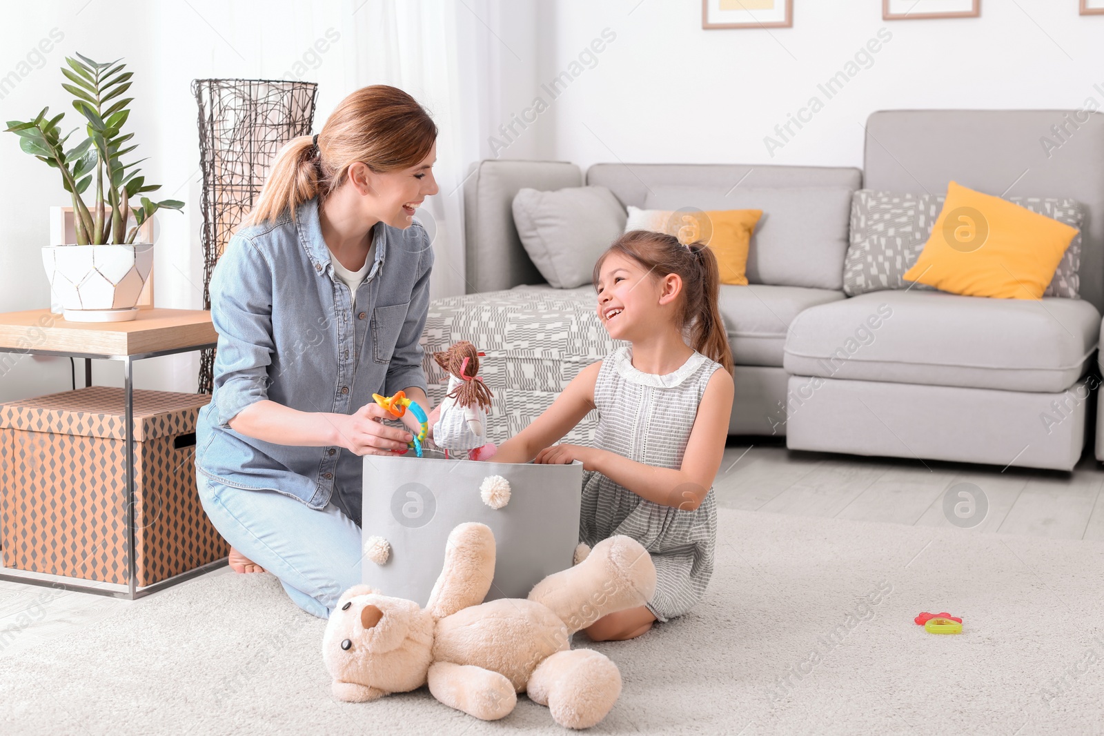 Photo of Housewife and daughter picking up toys after playing at home