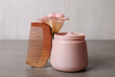 Hair product, flower and wooden comb on grey table