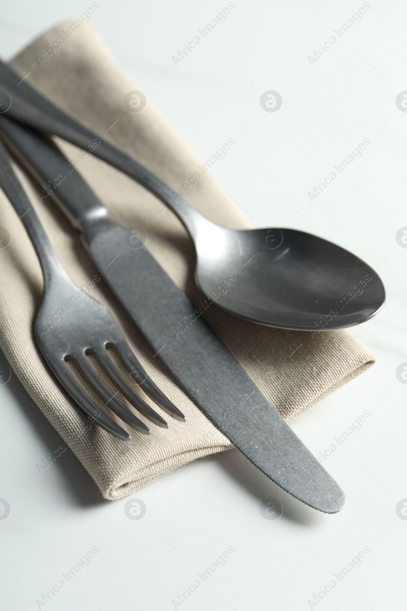 Photo of Stylish cutlery set and napkin on white table