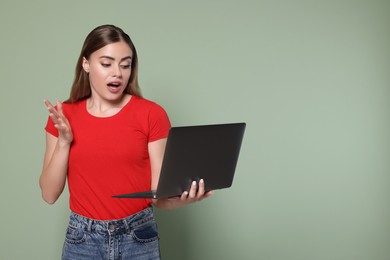 Photo of Emotional woman with laptop on pale green background. Space for text