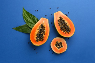 Fresh ripe papaya fruits with green leaves on blue background, flat lay