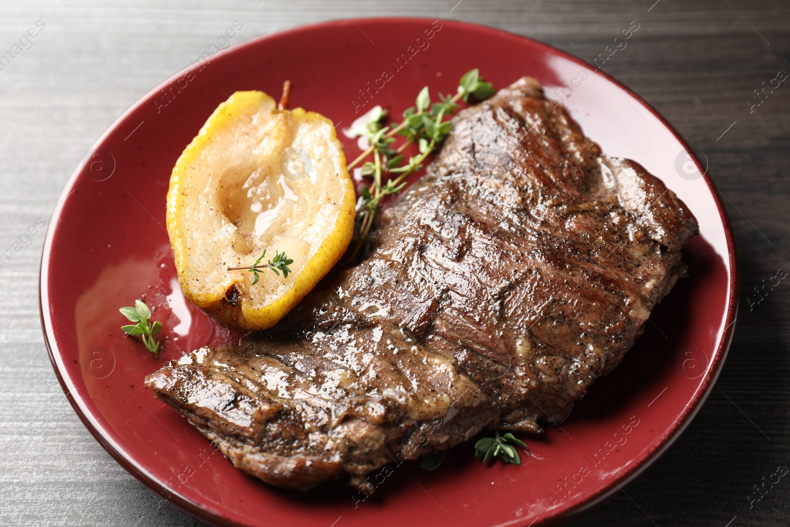 Photo of Delicious roasted beef meat, caramelized pear and thyme on grey wooden table, closeup