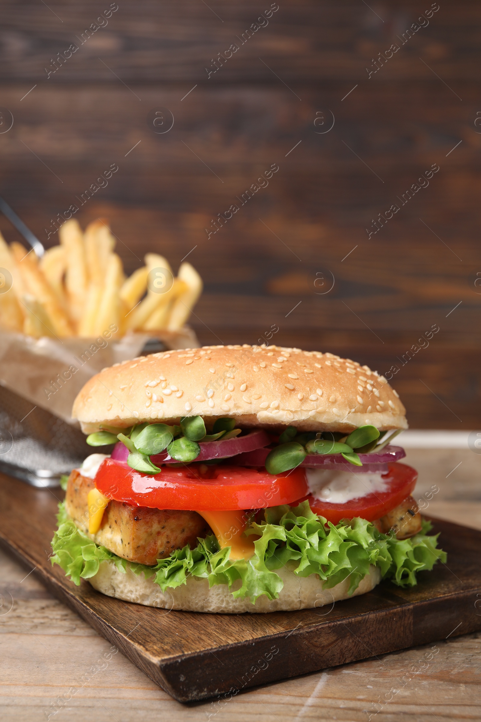 Photo of Delicious tofu burger served with french fries on wooden table