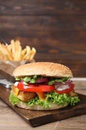 Photo of Delicious tofu burger served with french fries on wooden table