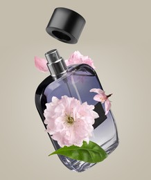 Image of Bottle of perfume and sakura flowers in air on greyish beige background