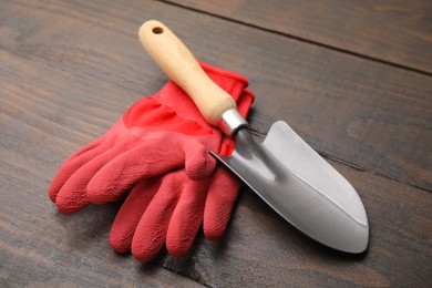 Photo of Gardening gloves and trowel on wooden table