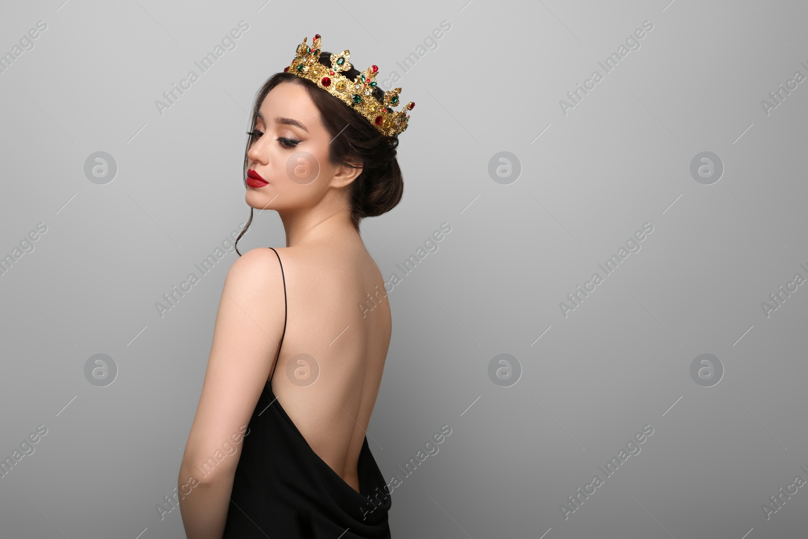 Photo of Beautiful young woman wearing luxurious crown on light grey background, space for text