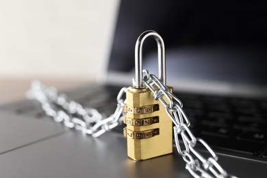 Photo of Cyber security. Laptop with padlock and chain on table, closeup