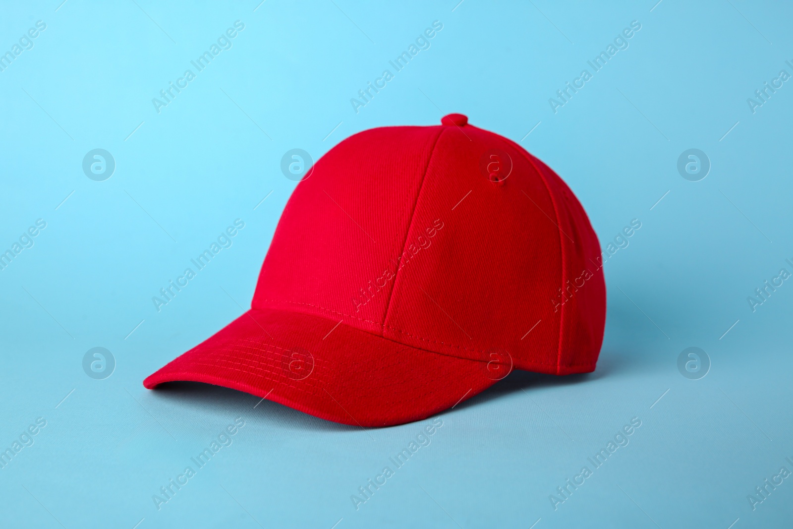 Photo of Stylish red baseball cap on light blue background