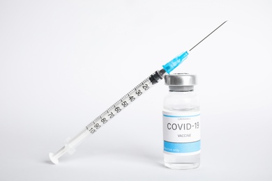 Photo of Vial with coronavirus vaccine and syringe on white background