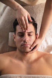 Photo of Man receiving facial massage in beauty salon, top view