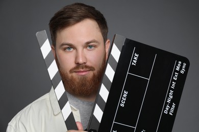 Making movie. Man with clapperboard on grey background