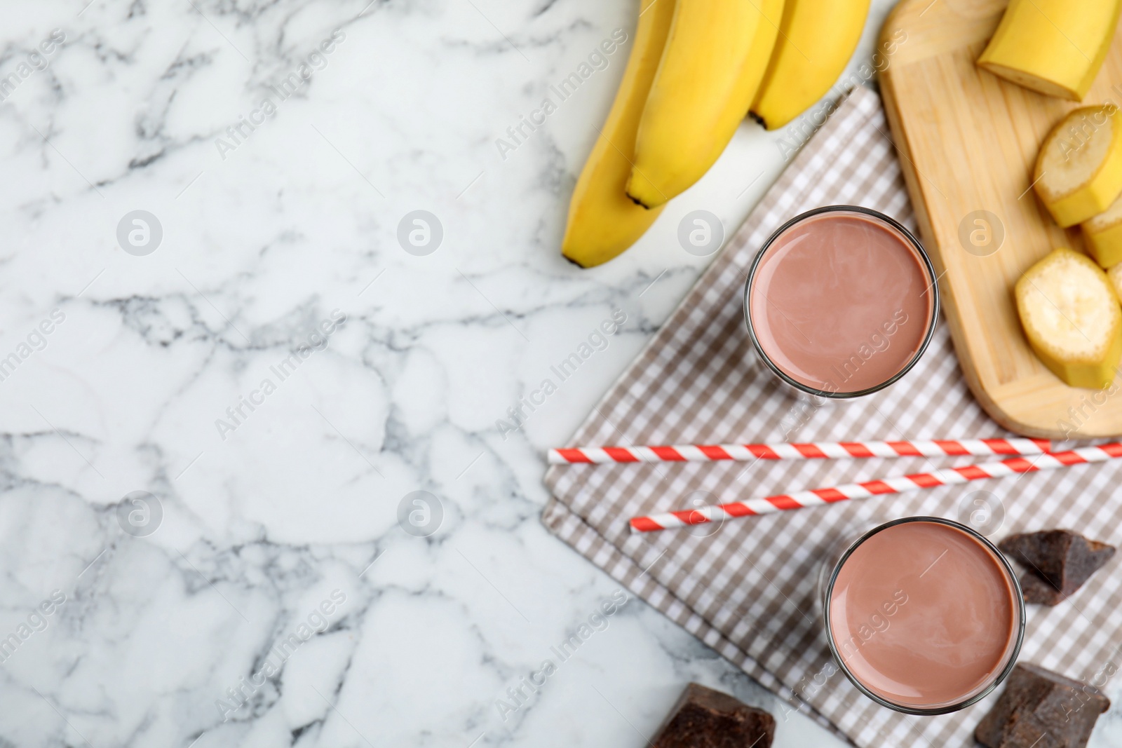 Photo of Yummy chocolate milk and fresh ingredients on white marble table, flat lay. Space for text