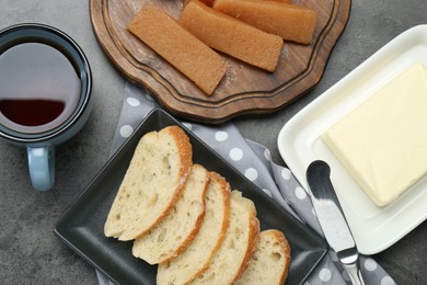 Photo of Delicious quince paste, bread, butter and cup of tea on grey textured table, flat lay