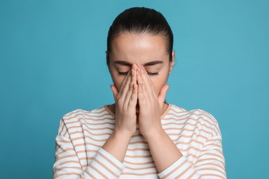 Photo of Young woman suffering from headache on light blue background