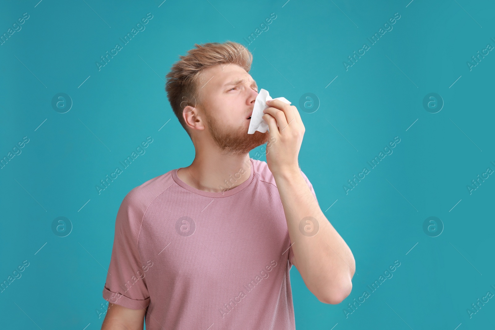Photo of Young man suffering from allergy on blue background