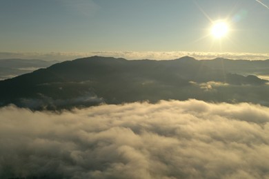 Photo of Aerial view of beautiful mountains covered with fluffy clouds on sunny day