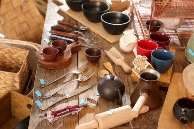 Many different cooking utensils on wooden table. Garage sale