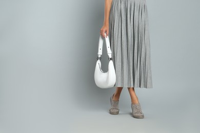 Photo of Woman with stylish bag on grey background, closeup. Space for text
