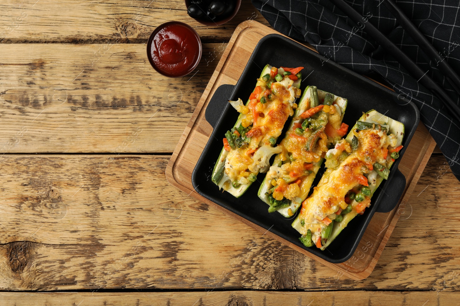 Photo of Baked stuffed zucchinis served on wooden table, flat lay. Space for text