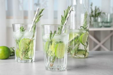 Photo of Tasty refreshing cocktail with rosemary and lime on table