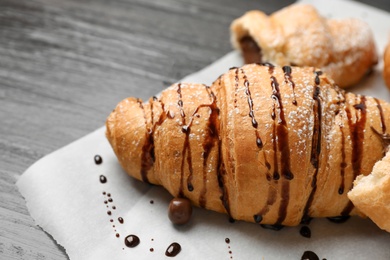 Photo of Tasty croissant with chocolate sauce, closeup