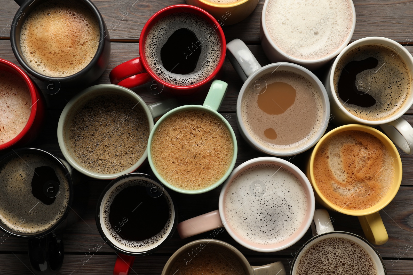 Photo of Many different cups with aromatic coffee on wooden table, flat lay