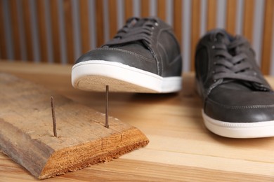 Nails in wooden plank and shoes on table