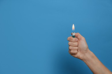 Photo of Woman holding lighter on light blue background, closeup. Space for text