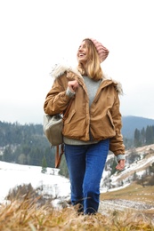 Young woman in warm clothes near snowy hill. Winter vacation